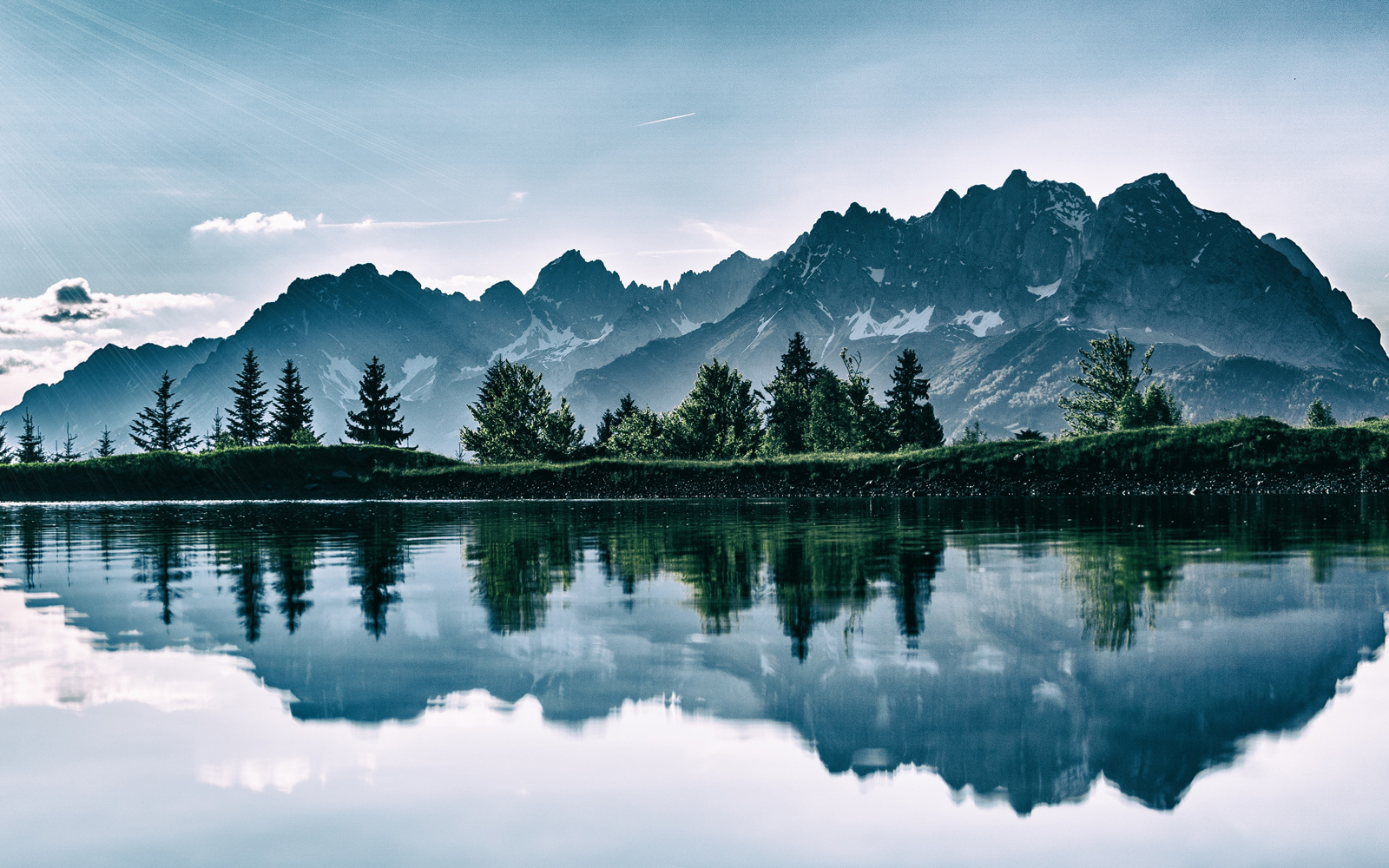 light shines over the mountains reflected in the calm waters of the lake.